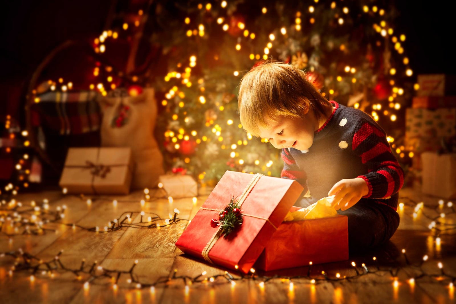 Nen obrint un regal sota l'arbre de Nadal