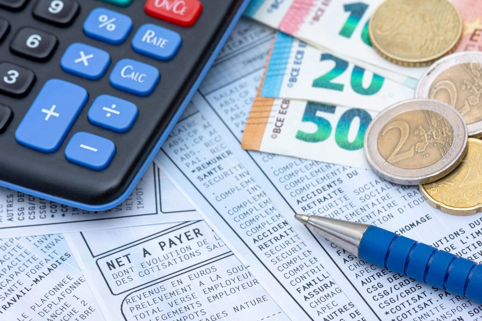 Calculatrice, billets en euros et bulletin de salaire pour calculer un acompte avant la paie d'octobre