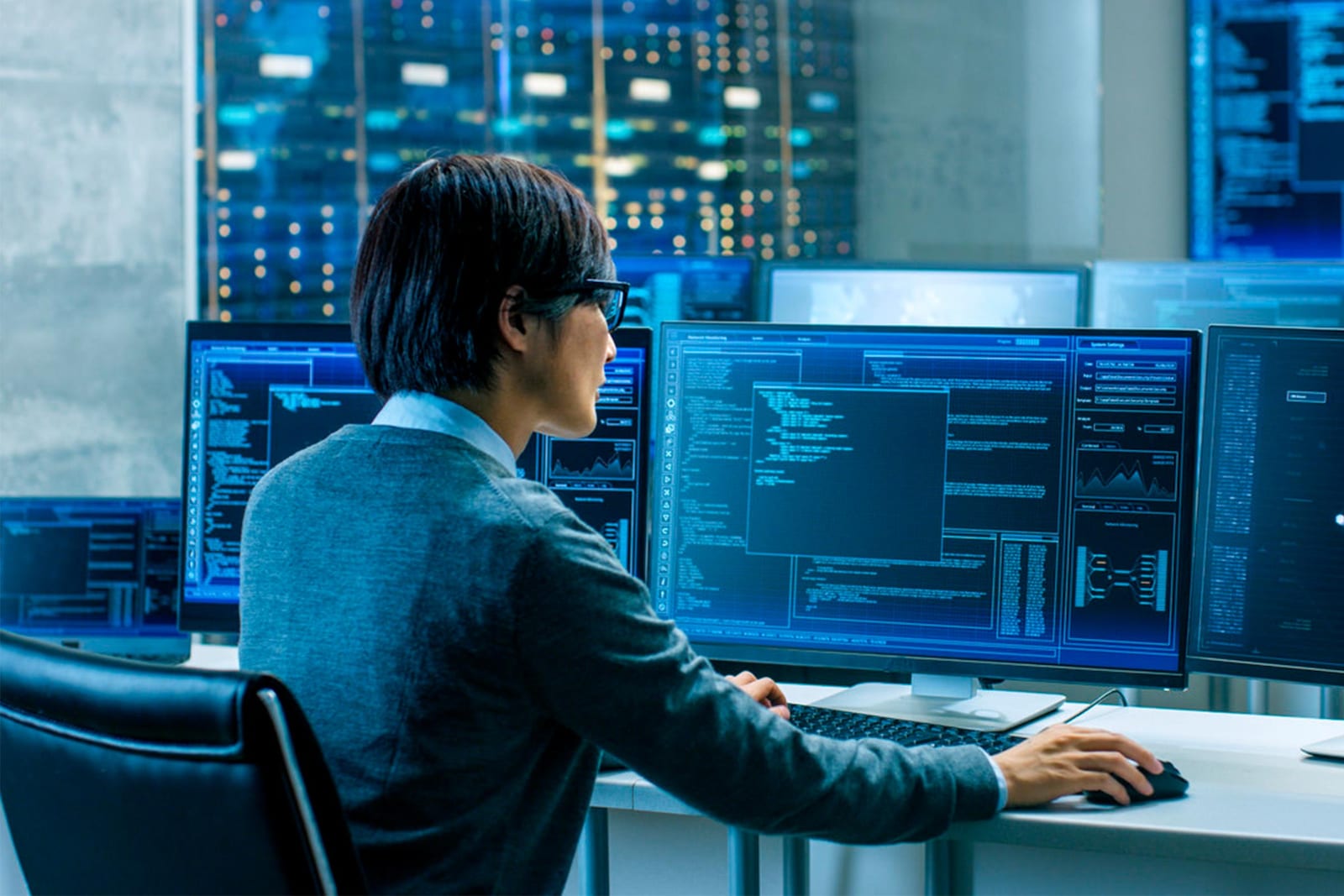 Hombre mirando varios ordenadores con datos