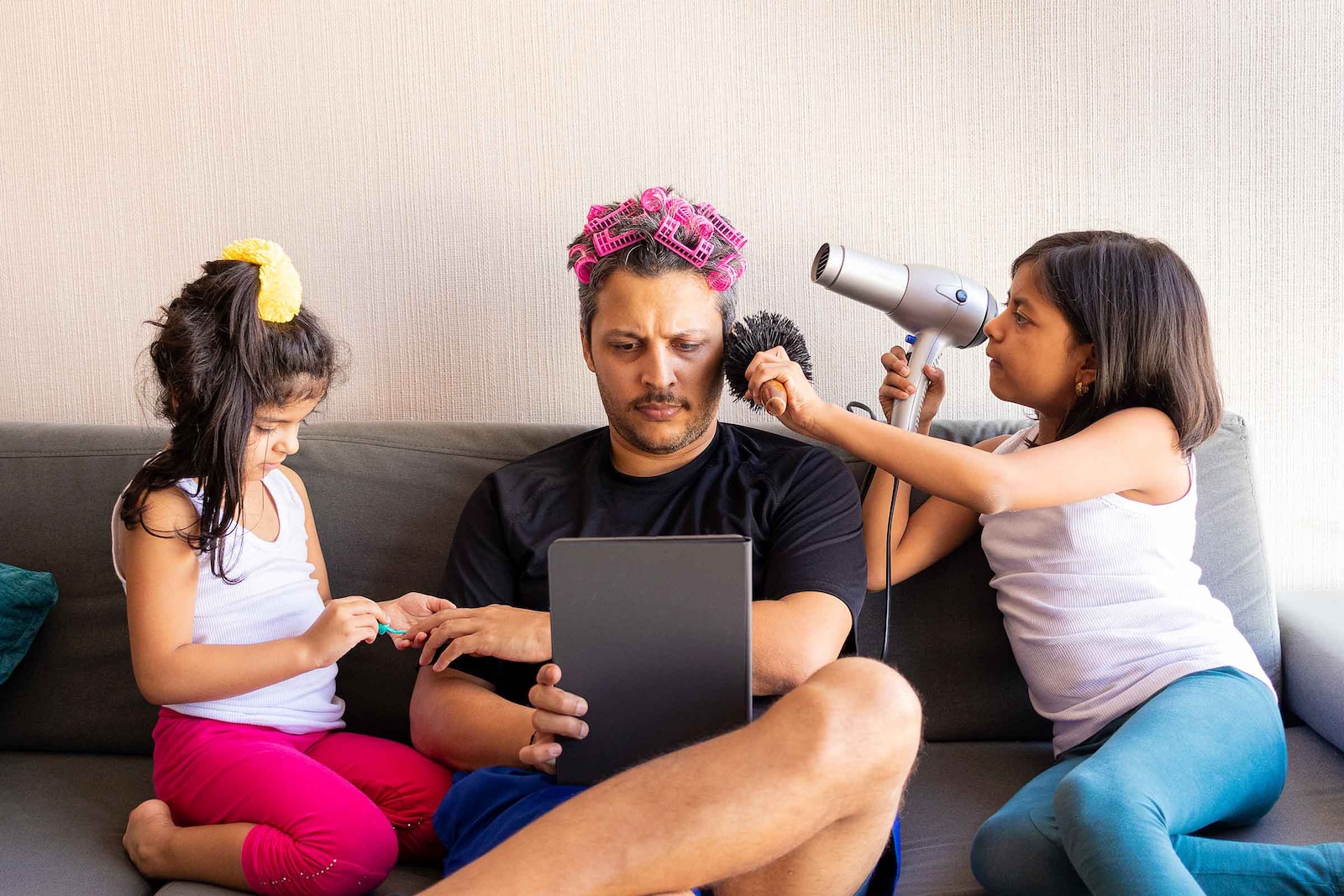 Padre jugando con sus hijas mientras le peinan 