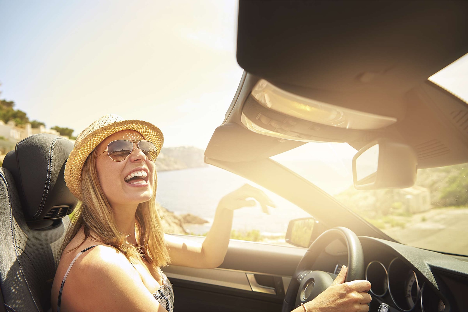 Mujer conduciendo alegre su coche al atardecer