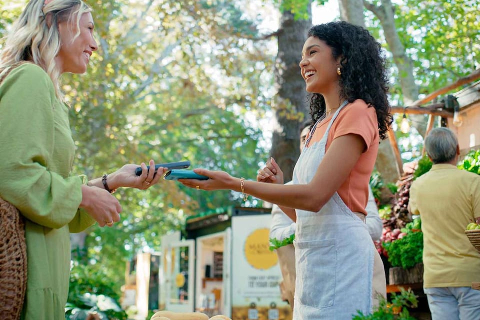 An employee takes payment from a customer at an outdoor event using BBVA's mobile POS terminal