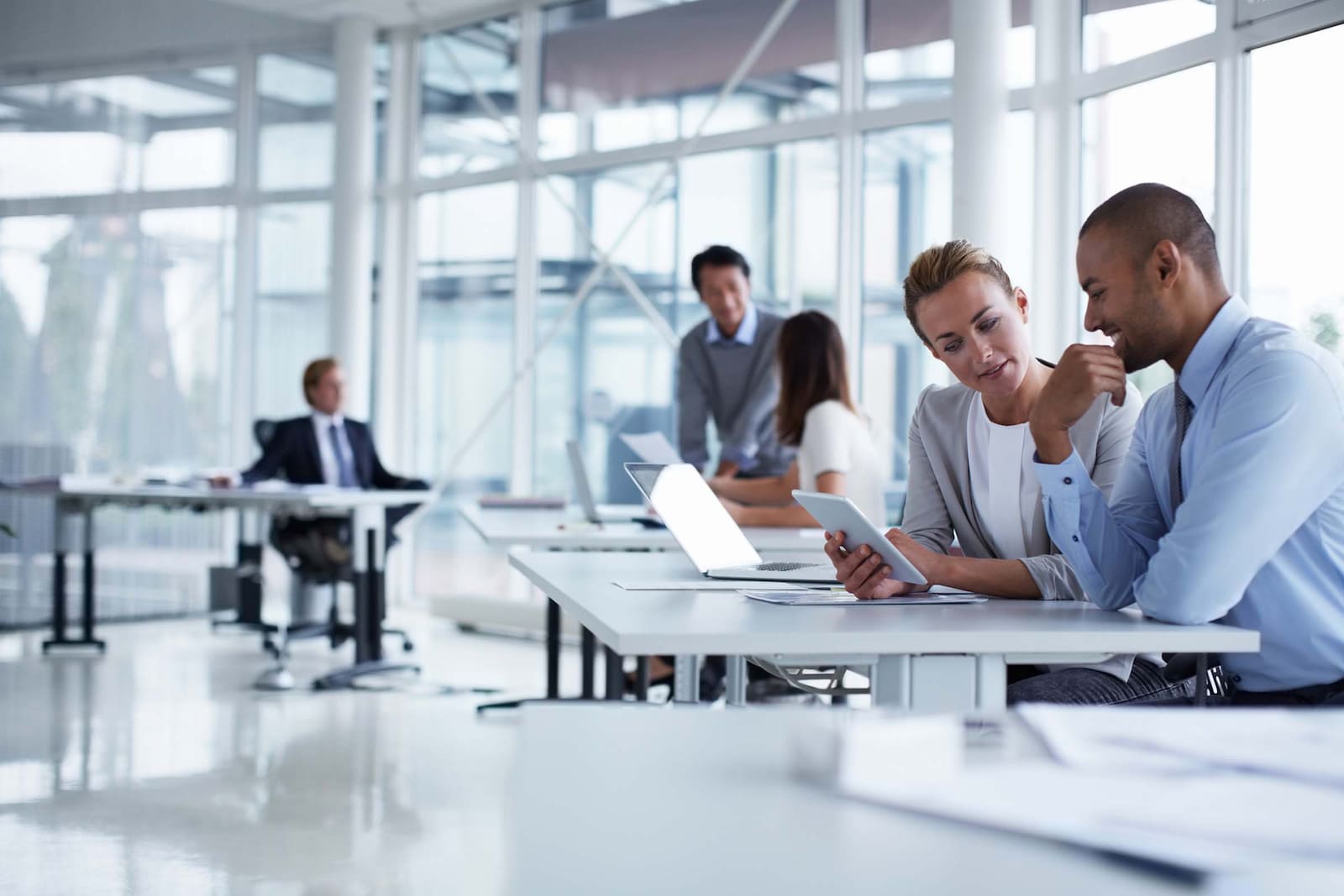 Empresario y trabajadores conversando en la oficina, mientras analizan los datos de la empresa.