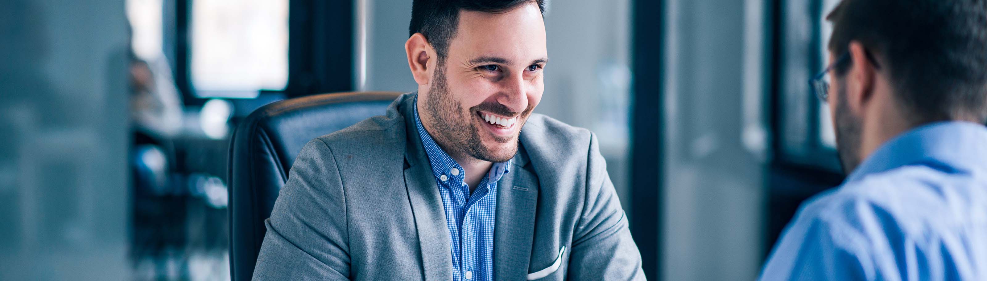 Empresario sonriente en reunión de negocios, simbolizando las ventajas de estrenar un nuevo banco para su empresa