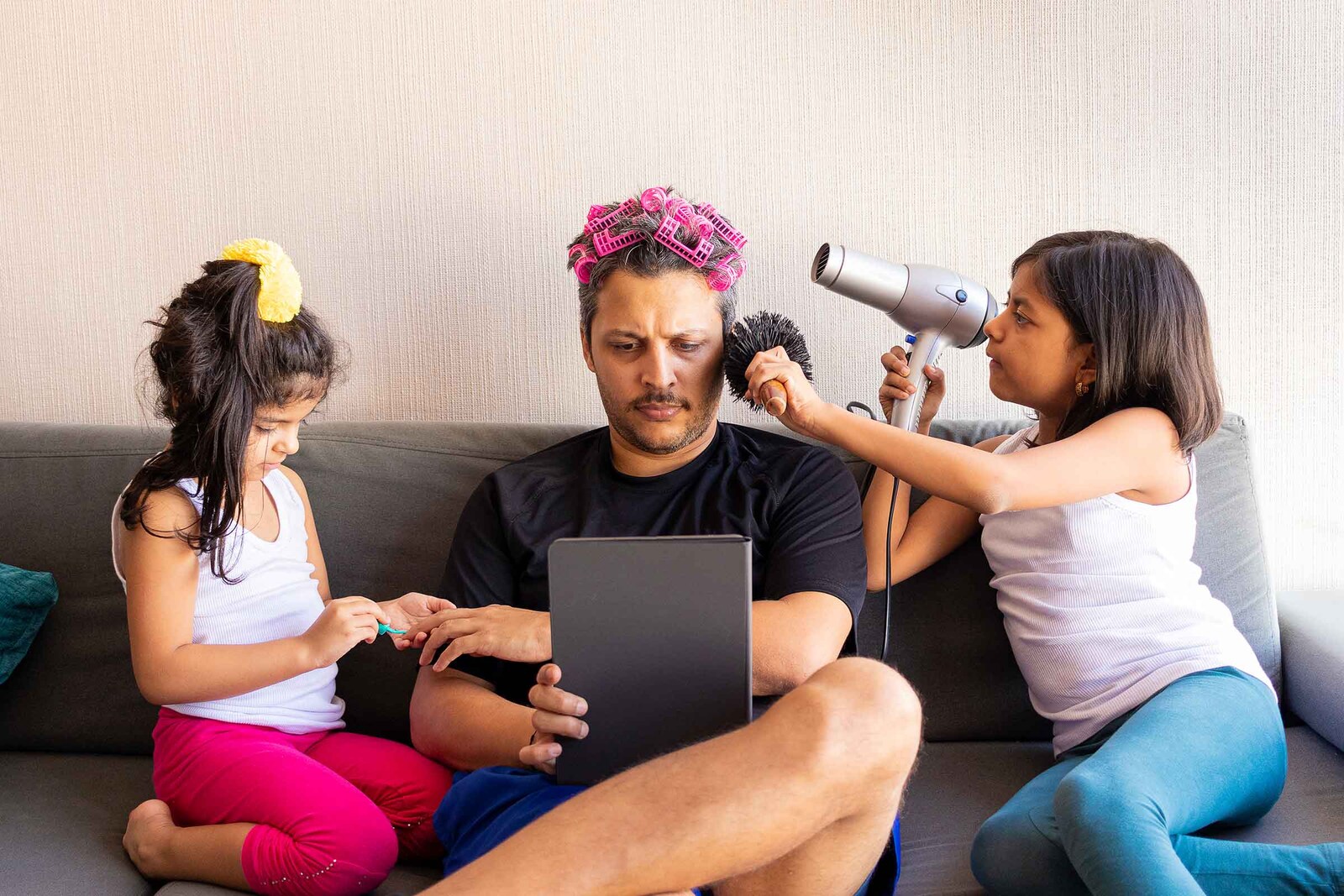 Father playing with his daughters while they comb his hair  