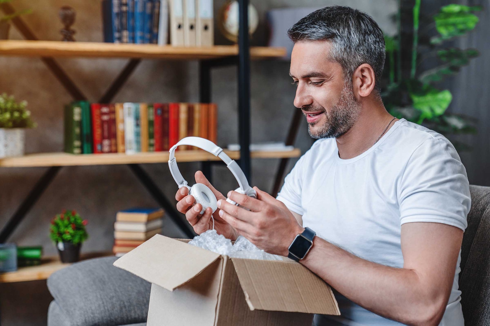 Home abrindo un paquete que acaba de recibir e sacando uns auriculares